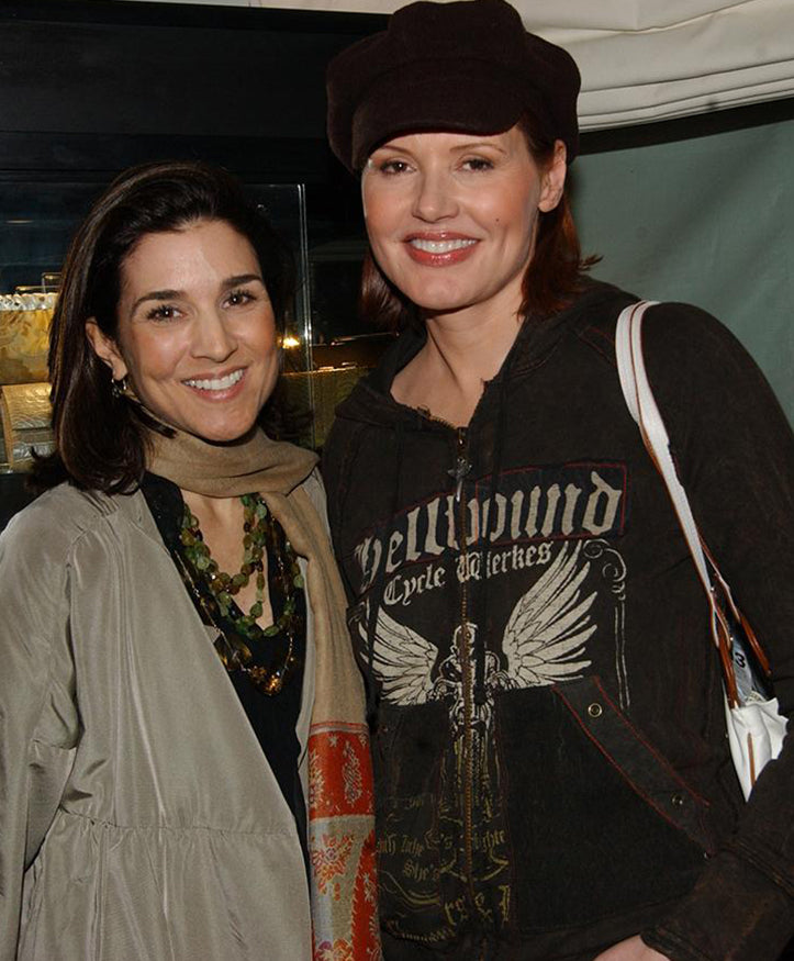 Designer Darby Scott and Geena Davis in front of case line of Darby Scott clutches and evening bags