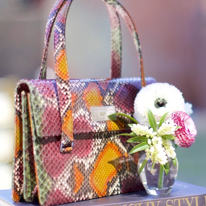 Emelia Monogram Handbag in python with vase and flowers in front