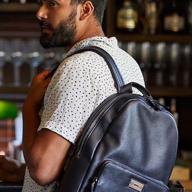 Man at bar with navy leather backpack - Darby Scott