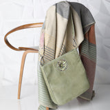 Autumnal colored Blanket with Green Suede Cloe Bag on back of a chair