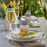 Festive table setting with glasses of champagne, dinnerware, and packages of shortbread cookies