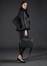 Model carrying a Newport Travel Satchel Bag - Black Leather Weekender